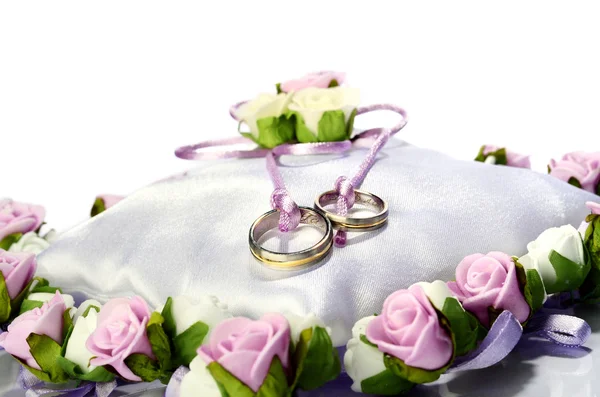 Anéis de casamento dourados isolados no travesseiro branco com flores — Fotografia de Stock