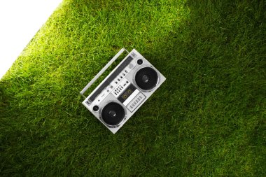 Retro boom box receiver over fresh green grass clipart