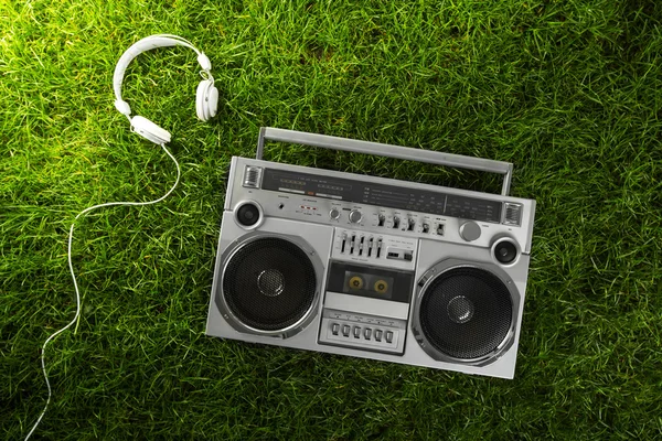 Retro-gestileerde zilveren boom box en oortelefoons over groen gras stud — Stockfoto