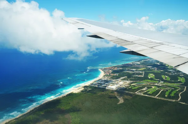 Ala de um avião voando acima das nuvens sobre a ilha tropical — Fotografia de Stock