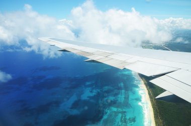 Bulutların üzerinde tropikal ada üzerinde uçan bir uçağın kanat