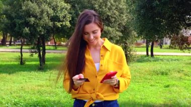 Akıllı telefon kullanan ve dışarıda kredi kartı tutan gülümseyen genç bir kadın. Online alışveriş, dijital ödeme, modern yaşam tarzı, ticaret, finans, bağlantı, teknoloji, özgürlük.