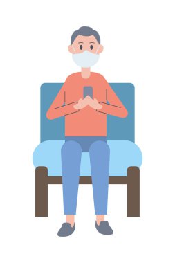 Kanepede oturan akıllı telefonu kullanarak maske takan genç bir adam.