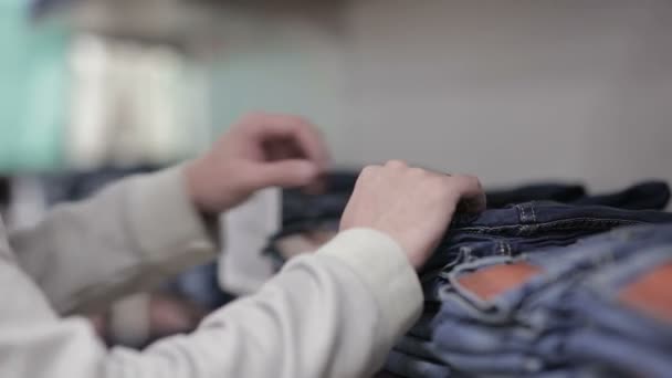 Hombre de mediana edad elige un jeans en la tienda — Vídeo de stock