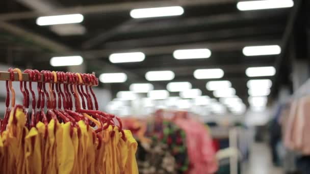 Various clothes on hangers in a store. slider shot — Stock Video