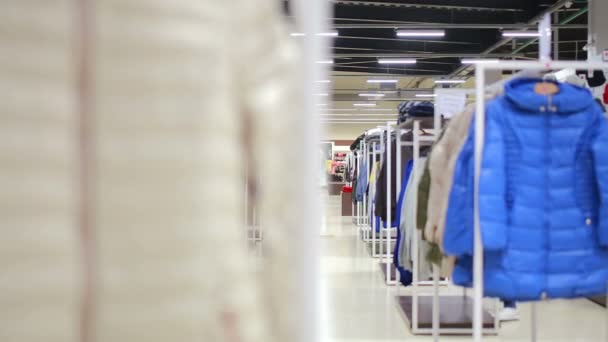 Various clothes on hangers in a store. slider shot — Stock Video