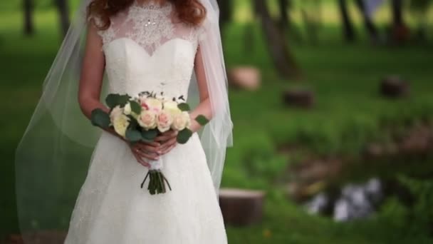 Noiva em um jardim enquanto segurando um buquê em mãos — Vídeo de Stock