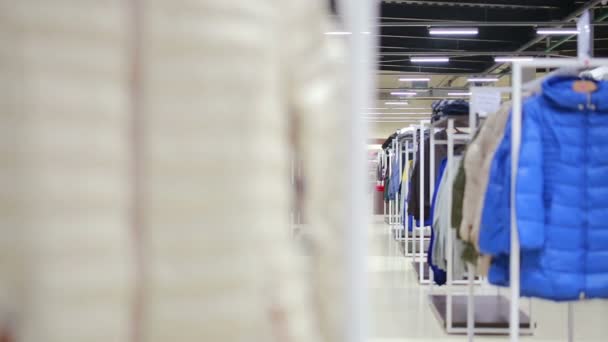 Various clothes on hangers in a store. slider shot — Stock Video