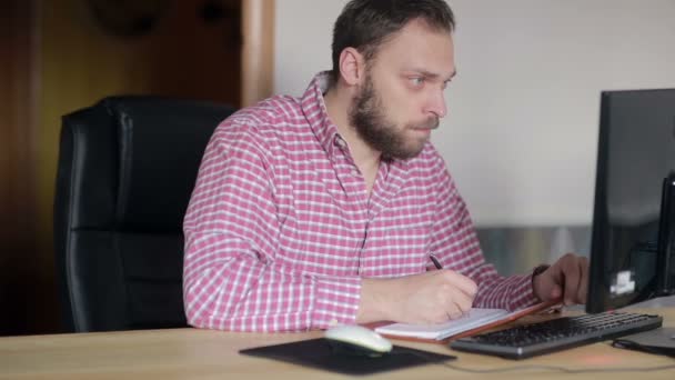 Homme vérifié avec un journal intime à l'ordinateur — Video