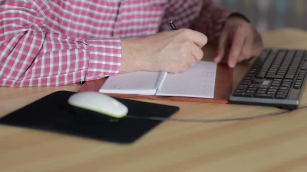 Man van de vergadering wordt om de computer en schrijven in het dagboek — Stockvideo