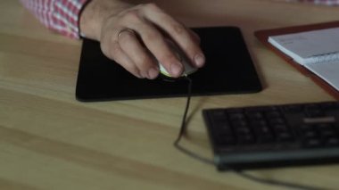 bir bilgisayar fare ile masada çalışan adam
