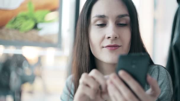 Hermosa mujer usando teléfono inteligente en la cafetería . — Vídeos de Stock