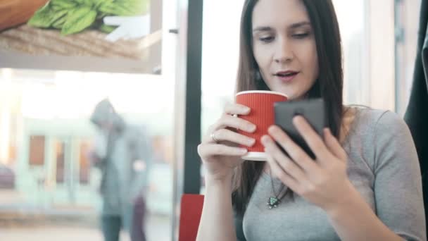Mulher usando smartphone, beber café no café . — Vídeo de Stock