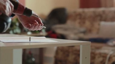 adam mobilya bir güç tornavida kullanarak birleştirir