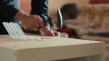 adam bir çekiç kullanarak mobilya parçaları birleştirir.