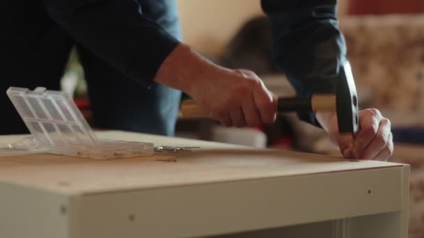 Homme assemble des pièces de meubles à l'aide d'un marteau . — Video