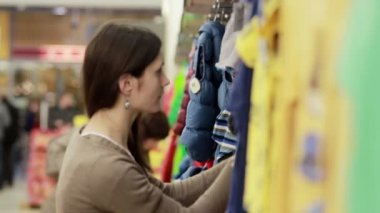 genç kadın giysileri bir çocuk için seçer.