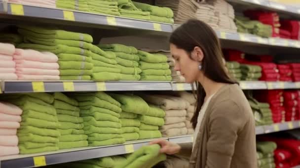 Jonge vrouw kiest handdoeken in de supermarkt — Stockvideo