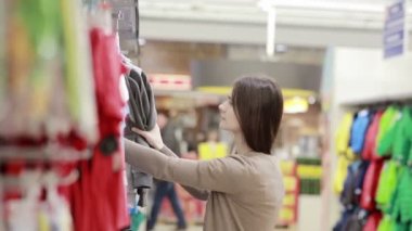 genç kadın giysileri bir çocuk için seçer.