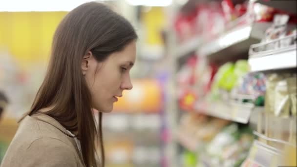 Девушка выбирает товар на полках в магазине — стоковое видео