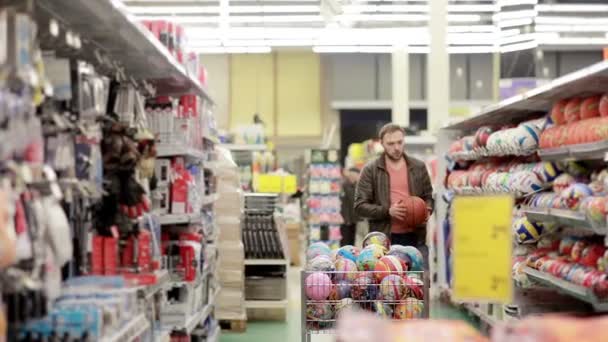 El hombre elige artículos deportivos en la tienda — Vídeos de Stock