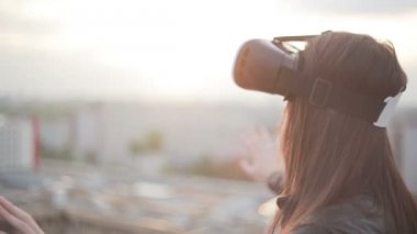 Kadın çatıda sanal gerçeklik gözlüğü kullanıyor.