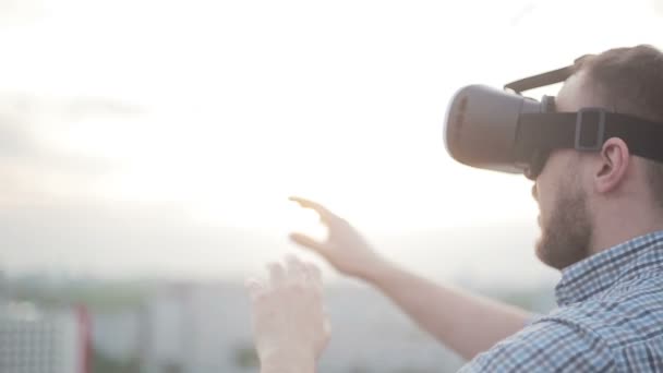 Мужчина использует очки виртуальной реальности на крыше — стоковое видео