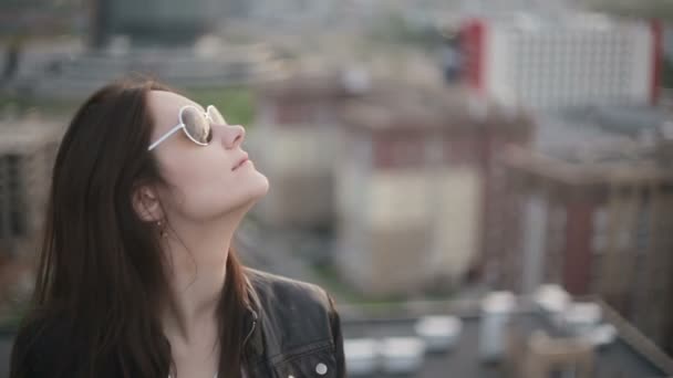 Girl in sunglasses standing on the roof at sunset — Stock Video