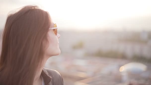 Chica en gafas de sol de pie en el techo al atardecer — Vídeo de stock