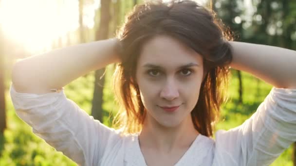 Kvinna i parken vid solnedgången rätar hår — Stockvideo