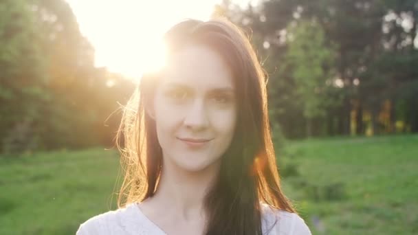 Улыбающаяся женщина под лучами заходящего солнца — стоковое видео