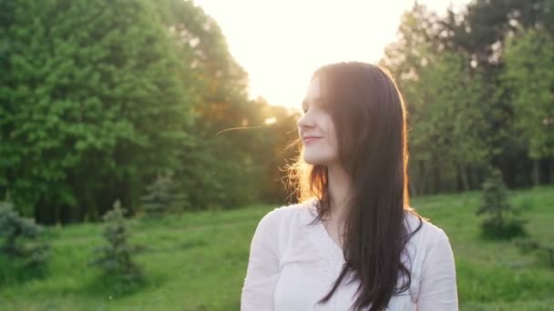 Femme heureuse dans un parc ou une forêt au coucher du soleil — Video