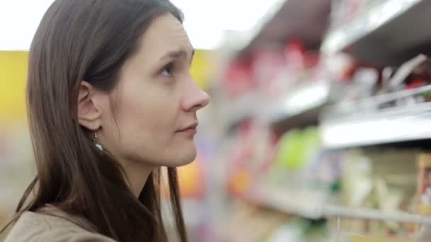 Девушка выбирает товар на полках в магазине — стоковое видео