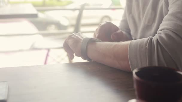 Człowiek z zegarka smartwatch, siedząc w kawiarni w mieście — Wideo stockowe