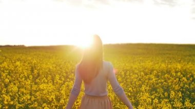 güzel kız çiçek sahada günbatımında yürür.