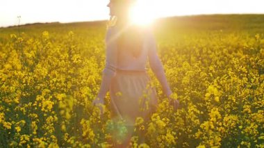 güzel kız çiçek sahada günbatımında yürür.