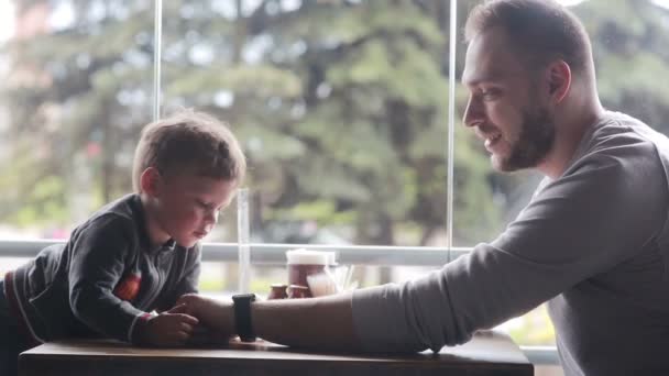 Мальчик смотрит на часы на отцовской руке — стоковое видео