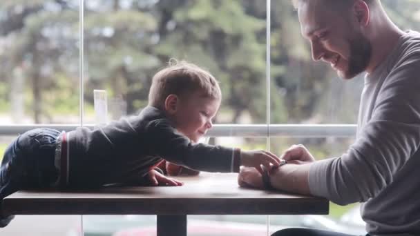 Liten pojke tittar på smartclock på fäders hand — Stockvideo