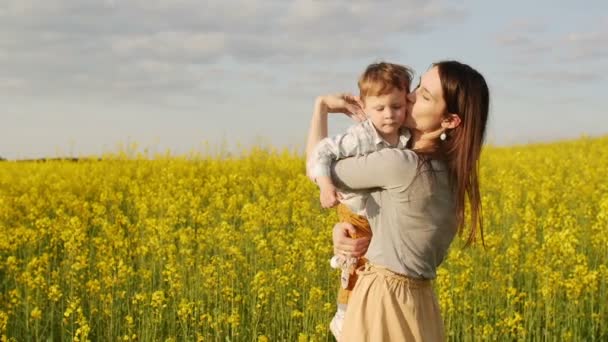 Moeder haar zoon houden op veld bij zonsondergang. Slow mo — Stockvideo