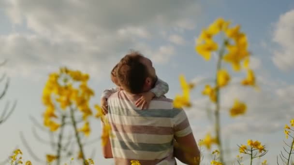 Отец обнимает своего сына на поле на закате. Слоумо — стоковое видео