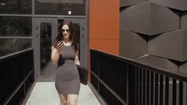 seksi iş kadını akıllı telefon kullanarak inşaat iş binası altında yürüyüş, steadicam vurdu. yavaş mo