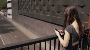 seksi iş kadını yol bakan bir köprü üzerinde duran akıllı telefon kullanarak, steadicam vurdu. yavaş mo