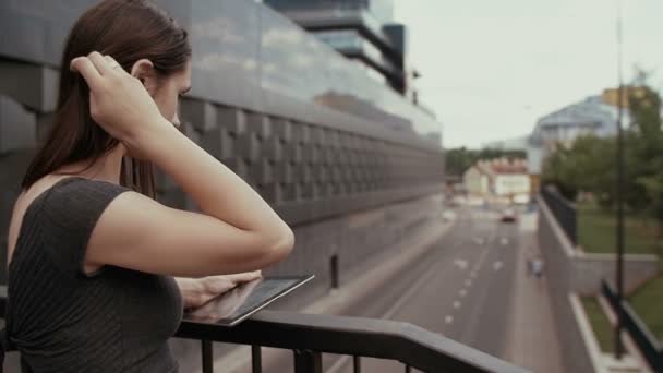 Mulher de negócios sexy usando tablet de pé em uma ponte com vista para a estrada, steadicam tiro. lento mo — Vídeo de Stock