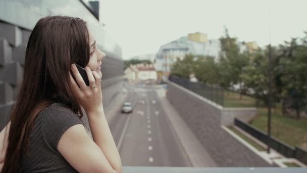 Sexy Geschäftsfrau mit Smartphone auf einer Brücke mit Blick auf die Straße stehen, Steadicam-Aufnahme. Langsames Wachstum — Stockvideo