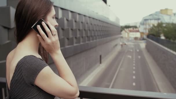 Сексуальная деловая женщина, использующая смартфон, стоящий на мосту с видом на дорогу, устойчивый снимок. медленное движение — стоковое видео