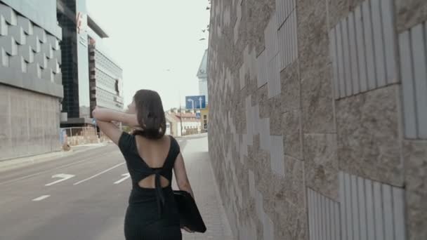 Sexy zakelijke vrouw wandelen op een stoep in het zakelijke centrum van de stad met haar aktetas, Steadicam geschoten. slow mo — Stockvideo