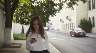 Woman uses smartphone walking in old city. slow mo