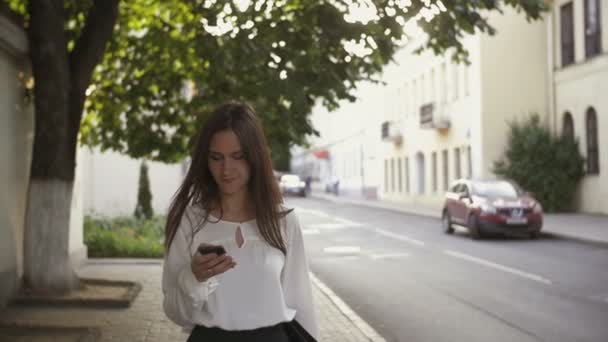 Woman uses smartphone walking in old city. slow mo — Stock videók