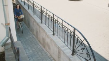 Bir sepet içinde çiçekler ve Fransız ekmeği ile sokakta bir bisiklet sürme saç sallayarak Muhteşem esmer kız, yavaş mo