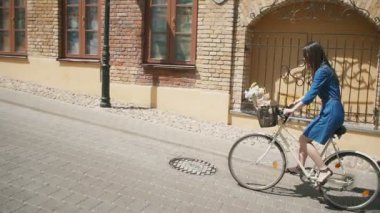Bir sepet içinde çiçeklerle yolda bisiklet ve şehir keşfetmek bir kızın yan görünümü, yavaş mo, steadicam atış